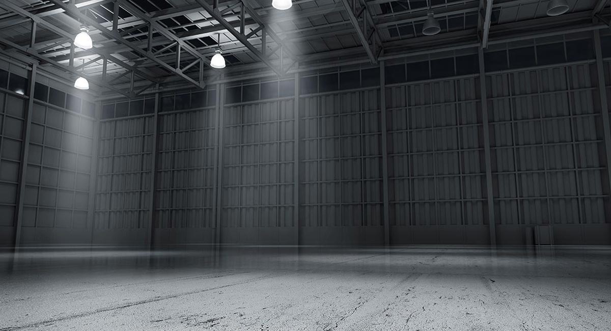 Dark gray corner of a warehouse with bright overhead lighting