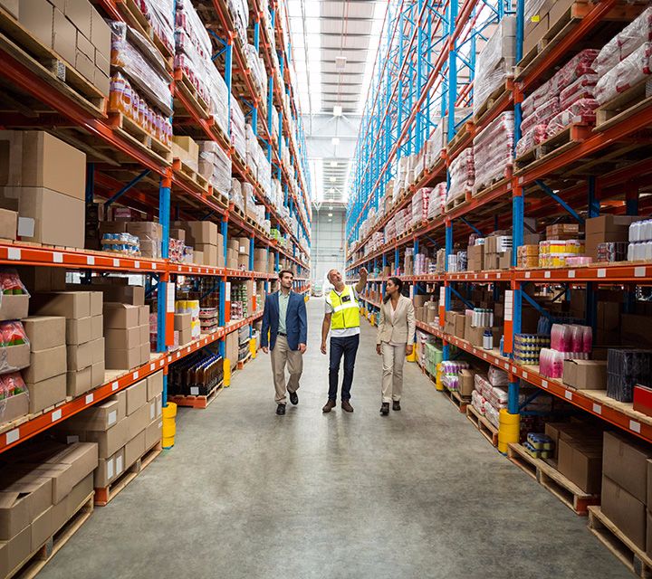 Group of people walking the aisle of a warehouse viewing the inventory